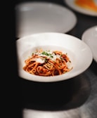 A steaming bowl of pasta garnished with herbs and cheese.