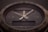 A close-up of a sophisticated wristwatch with a dark dial and luminescent hands. The bezel is marked with numbers, and there is a digital display beneath the hands indicating additional features. The brand name and model are subtly visible on the dial, indicating a premium design.