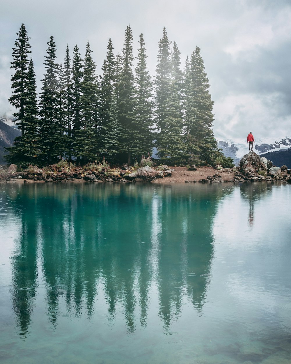 man standing on rock beside lake during daytime