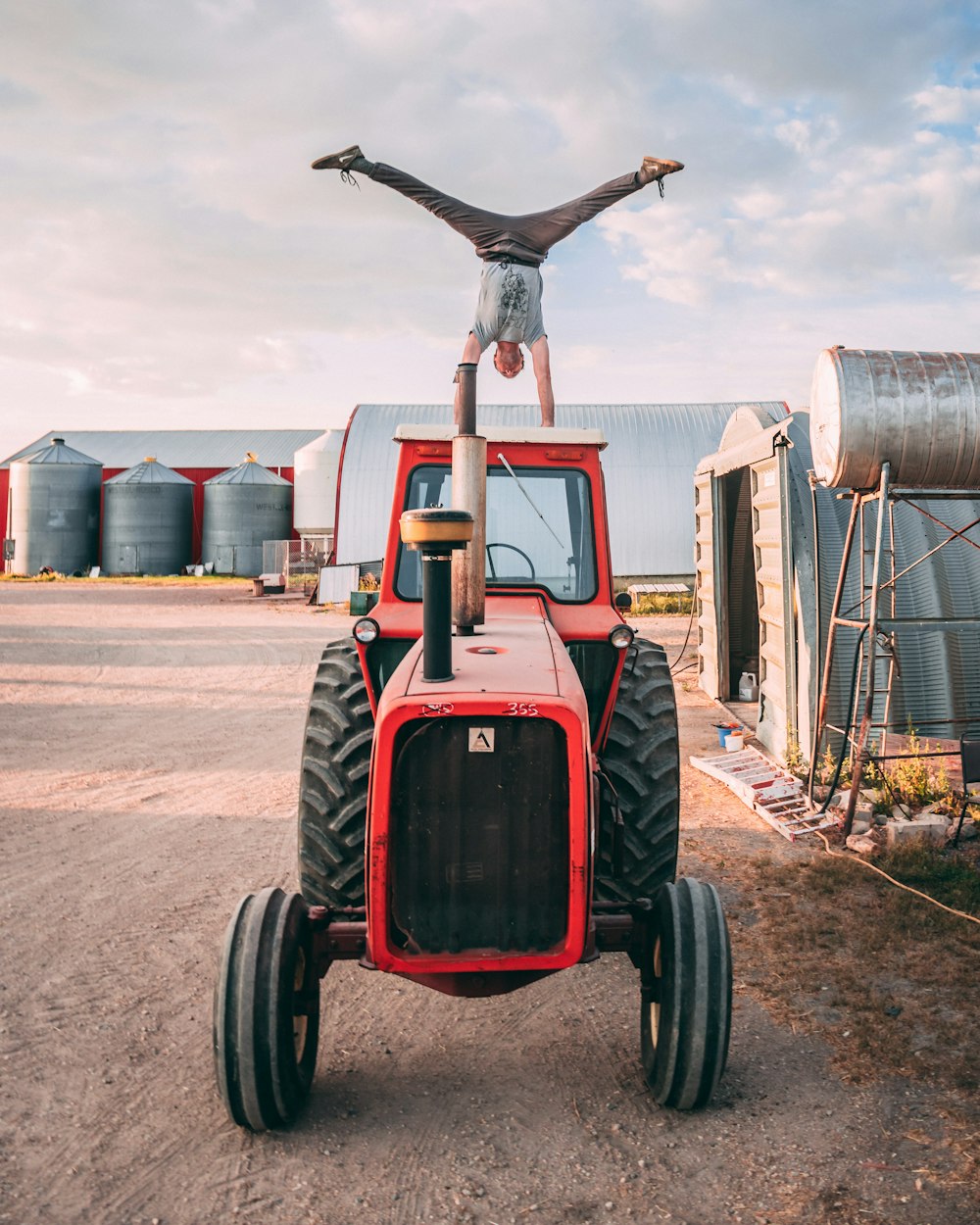 man doing head stand on red tractor