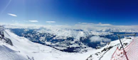 A panoramic view of a snow-covered mountain range with marked avalanche risk zones for education.