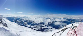 A panoramic view of a snow-covered mountain range with marked avalanche risk zones for education.