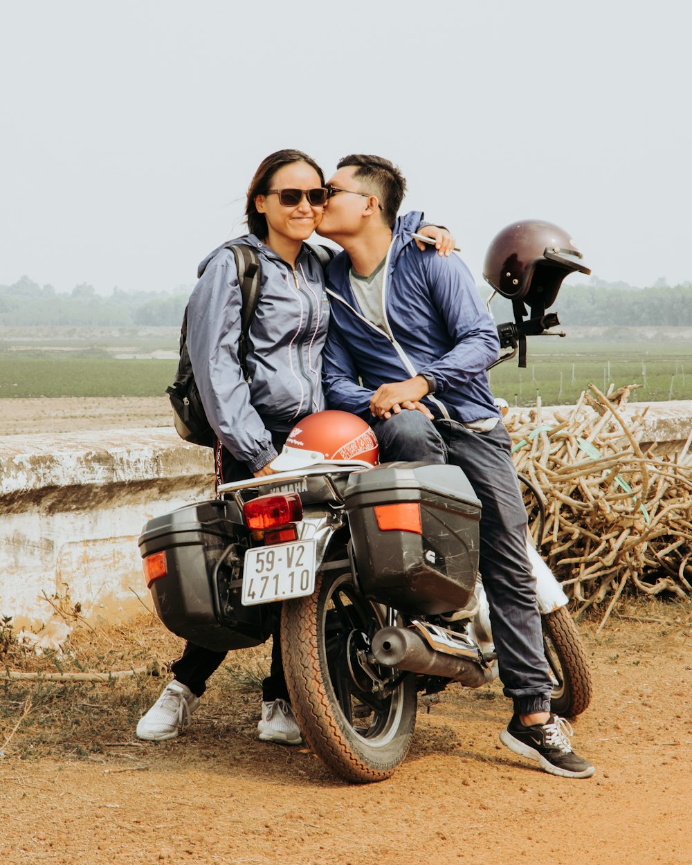 uomo in giacca grigia che bacia la donna mentre è seduto sulla moto