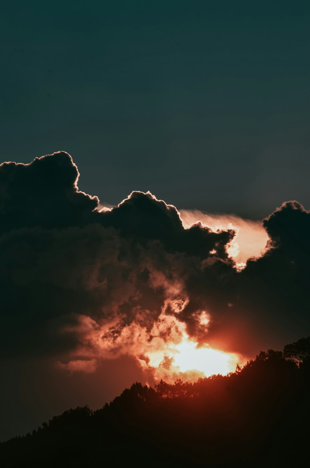 silhouette of mountain under cloudy sky during golden hour