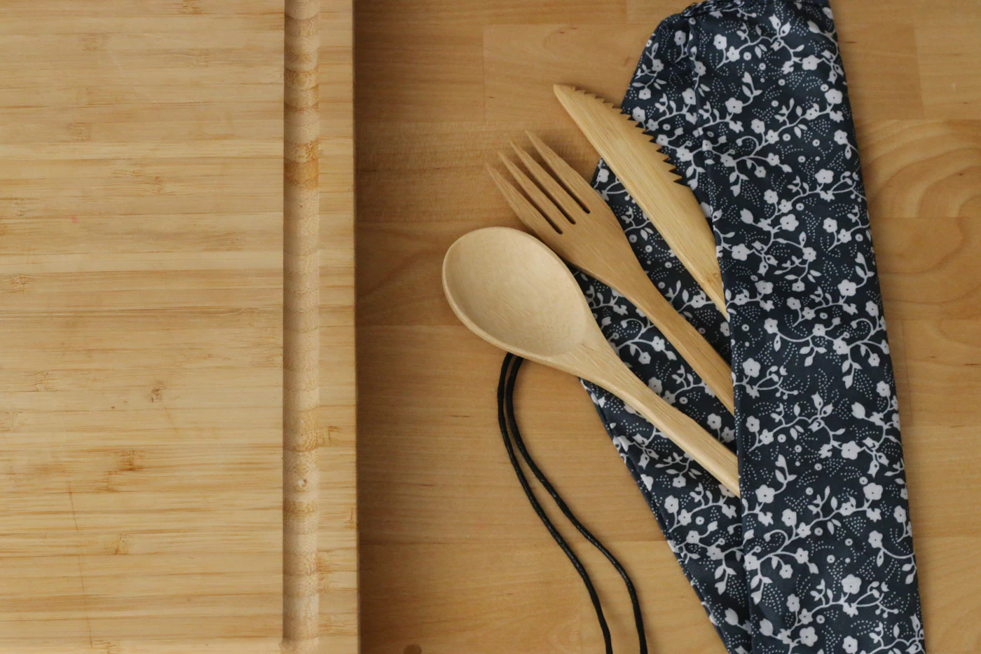 Cuillère, fourchette et couteau en bois posés sur une planche en bambou