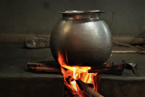 Traditional cooking pot simmering bright fruit jam over a wood stove.