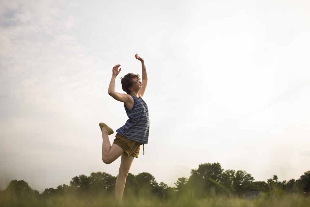 person standing raising right leg as well as both hands