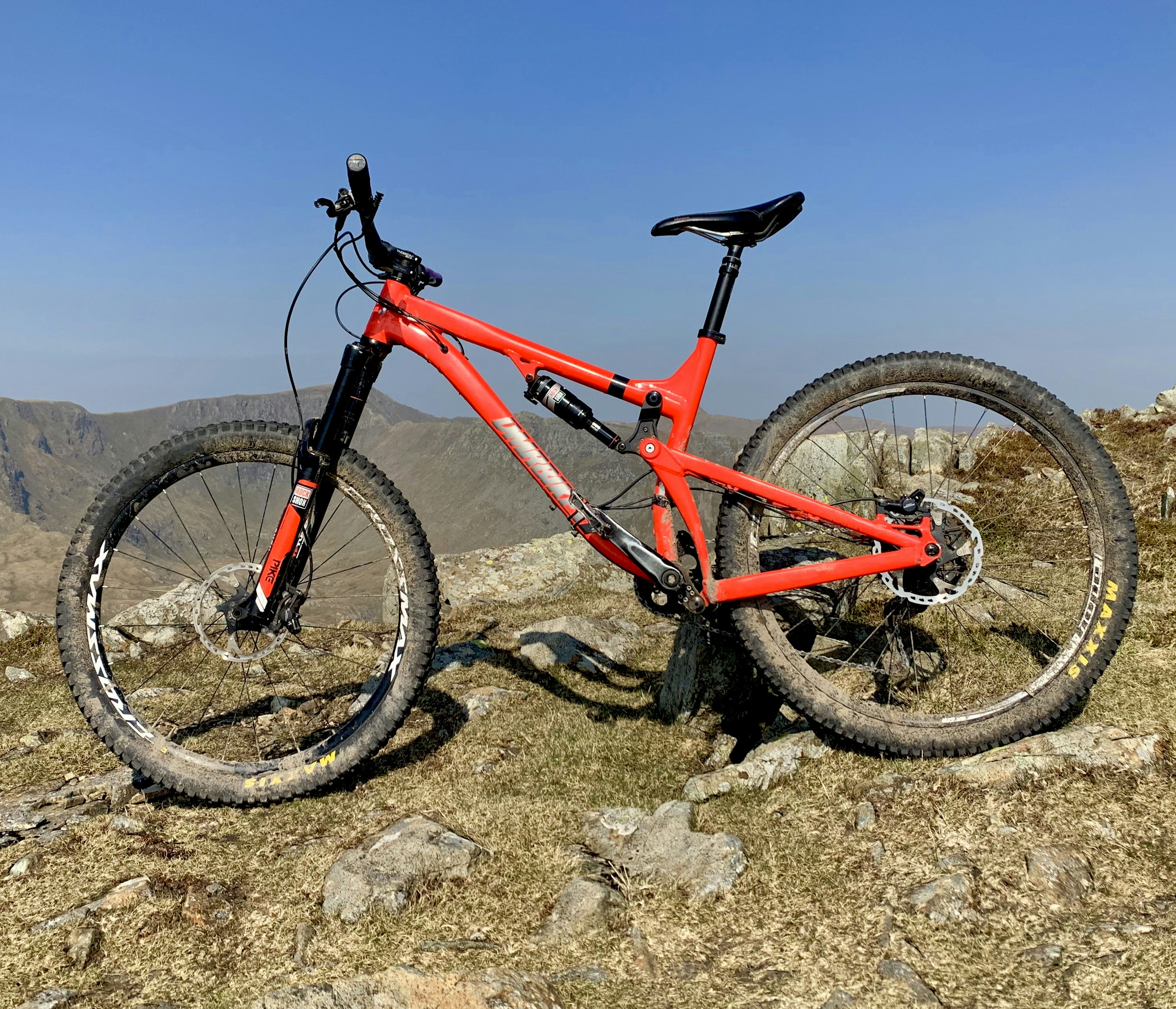 Red mountain bike on rocky trail, rugged terrain, bright afternoon sunlight