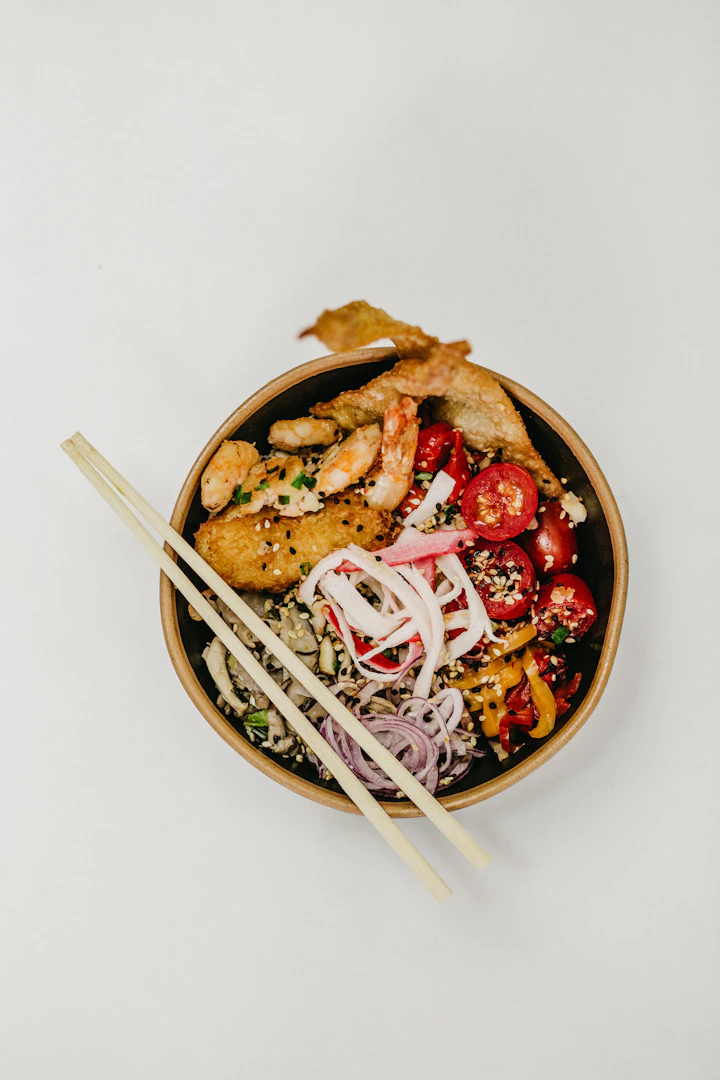 An overhead grain bowl with vegetables and sesame, ready to log
