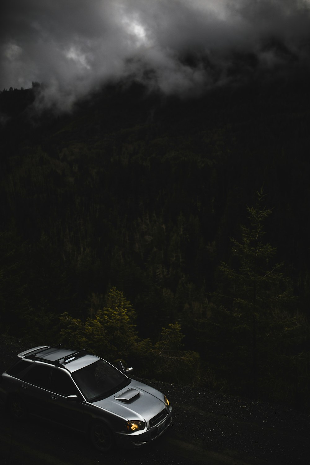 um carro dirigindo por uma estrada no meio de uma floresta