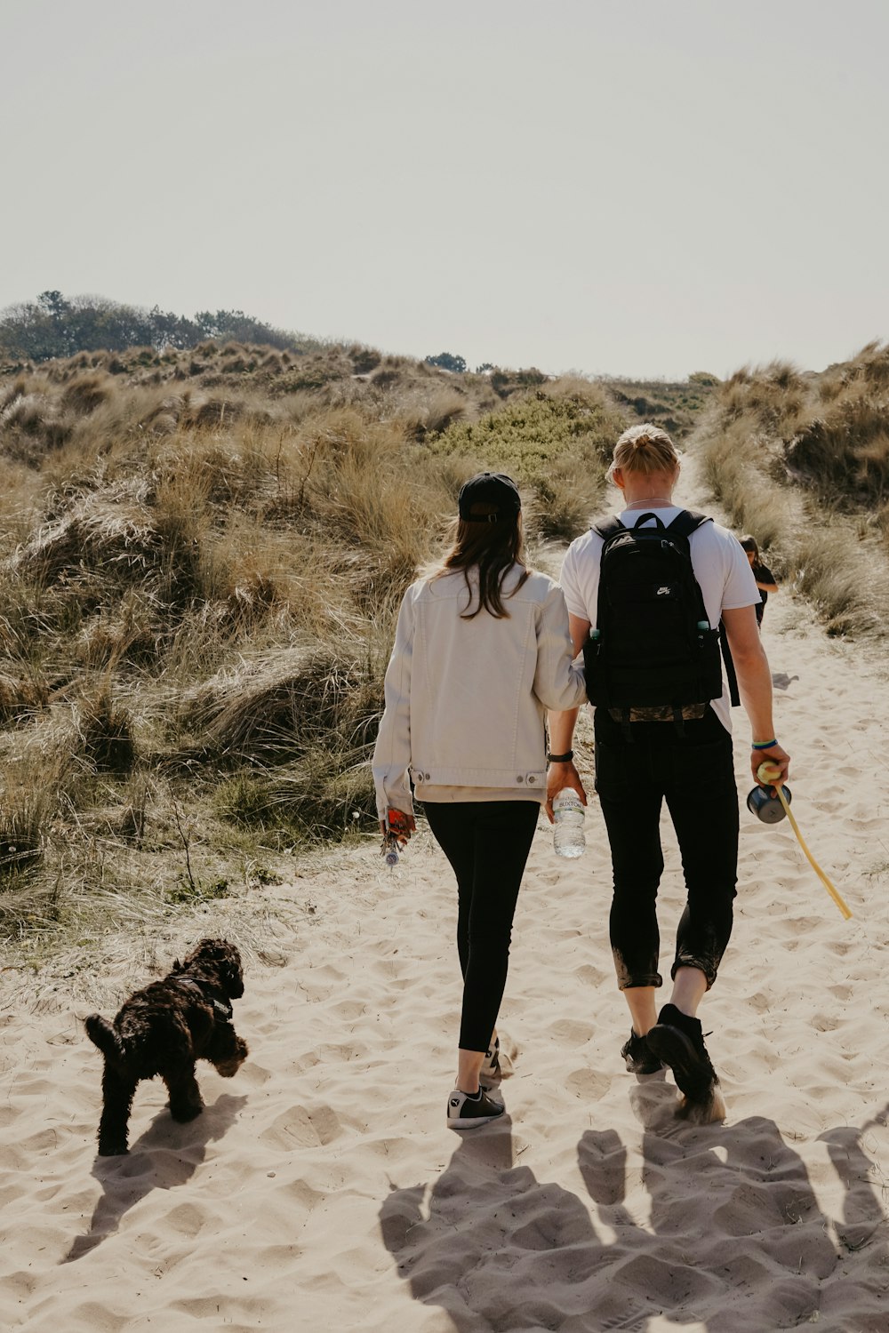 woman wearing white sweater besides man carrying black backpack