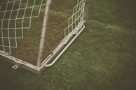 A close-up of a soccer ball on a field with goalposts in the background.