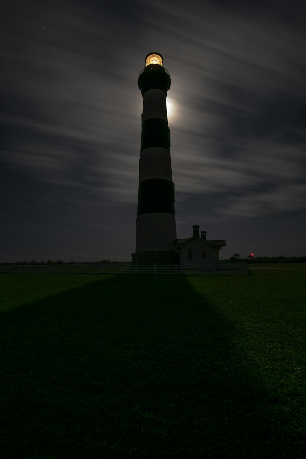 lighthouse under cloudy sky at night