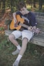 man playing guitar on bench while sitting