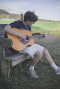 man playing brown acoustic guitar
