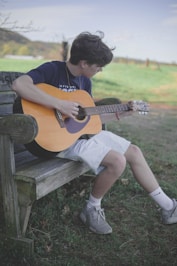 man playing brown acoustic guitar