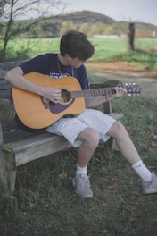 man playing brown acoustic guitar