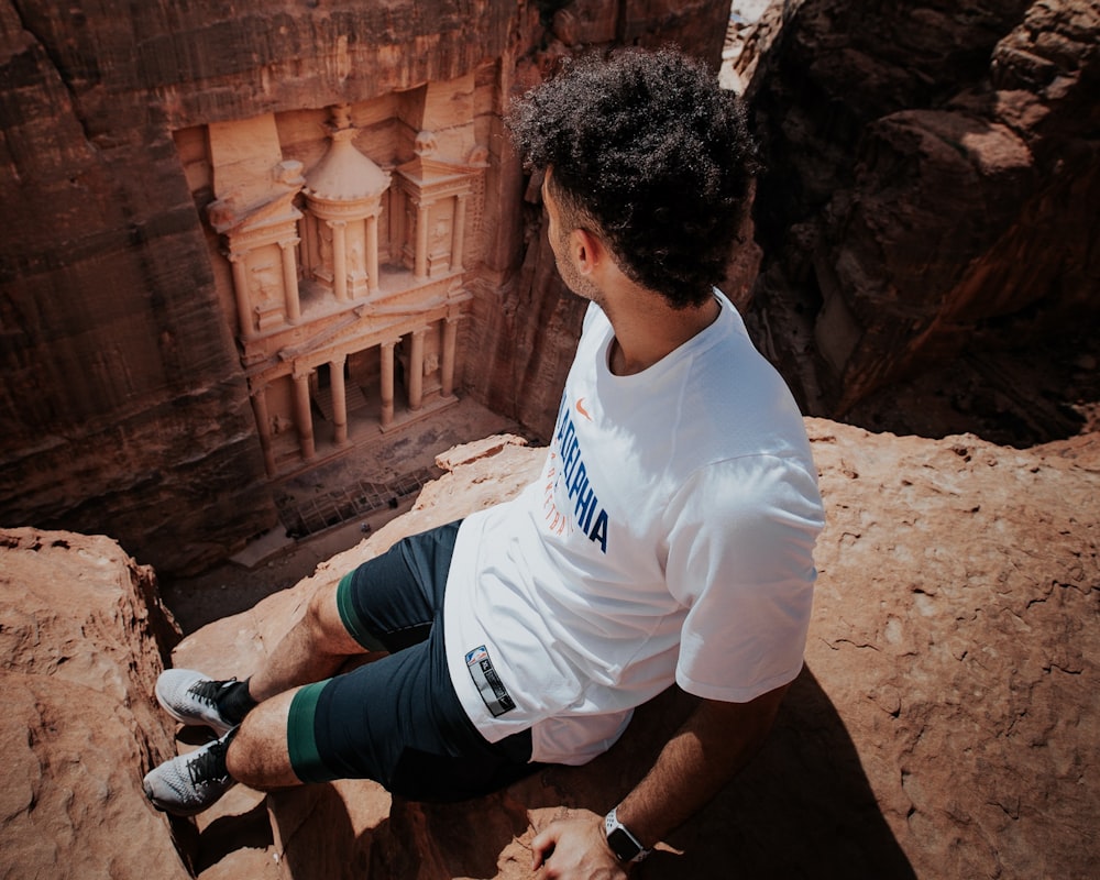 man in white t-shirt sitting on hill