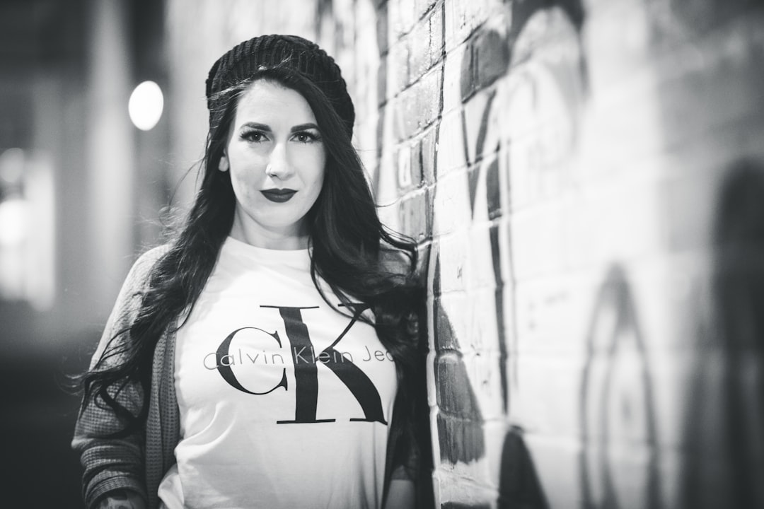 woman with knit cap and Calvin Klein shirt standing near wall