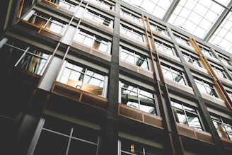 Construction team carefully measuring and framing a commercial building interior with natural light streaming through large windows.