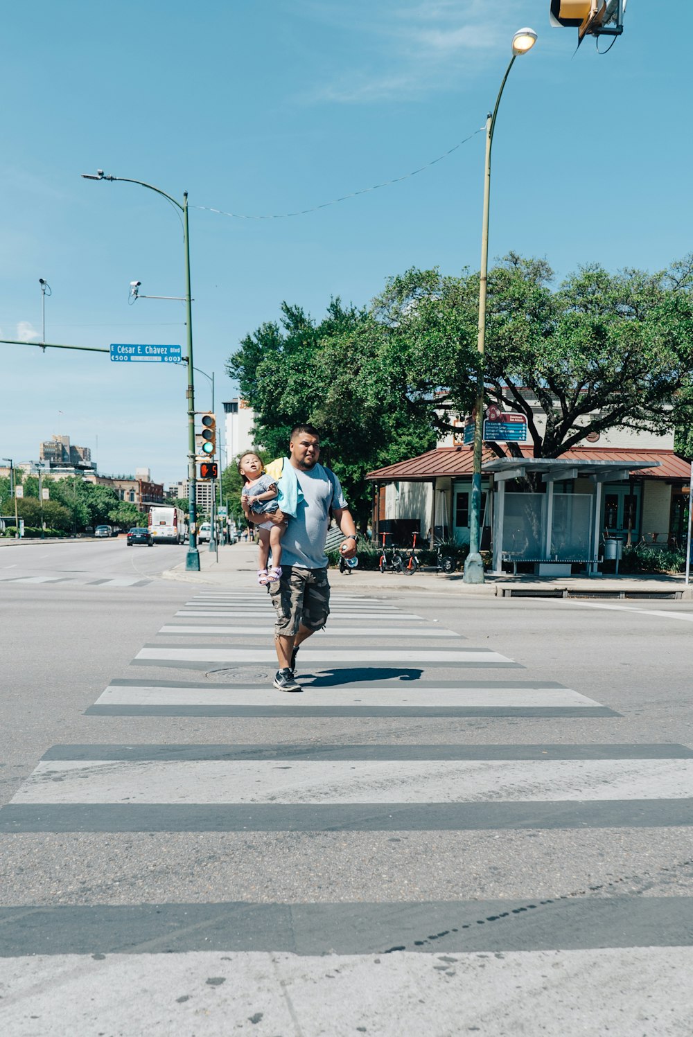 man wearing white carrying toddler crossing on pedestrian line