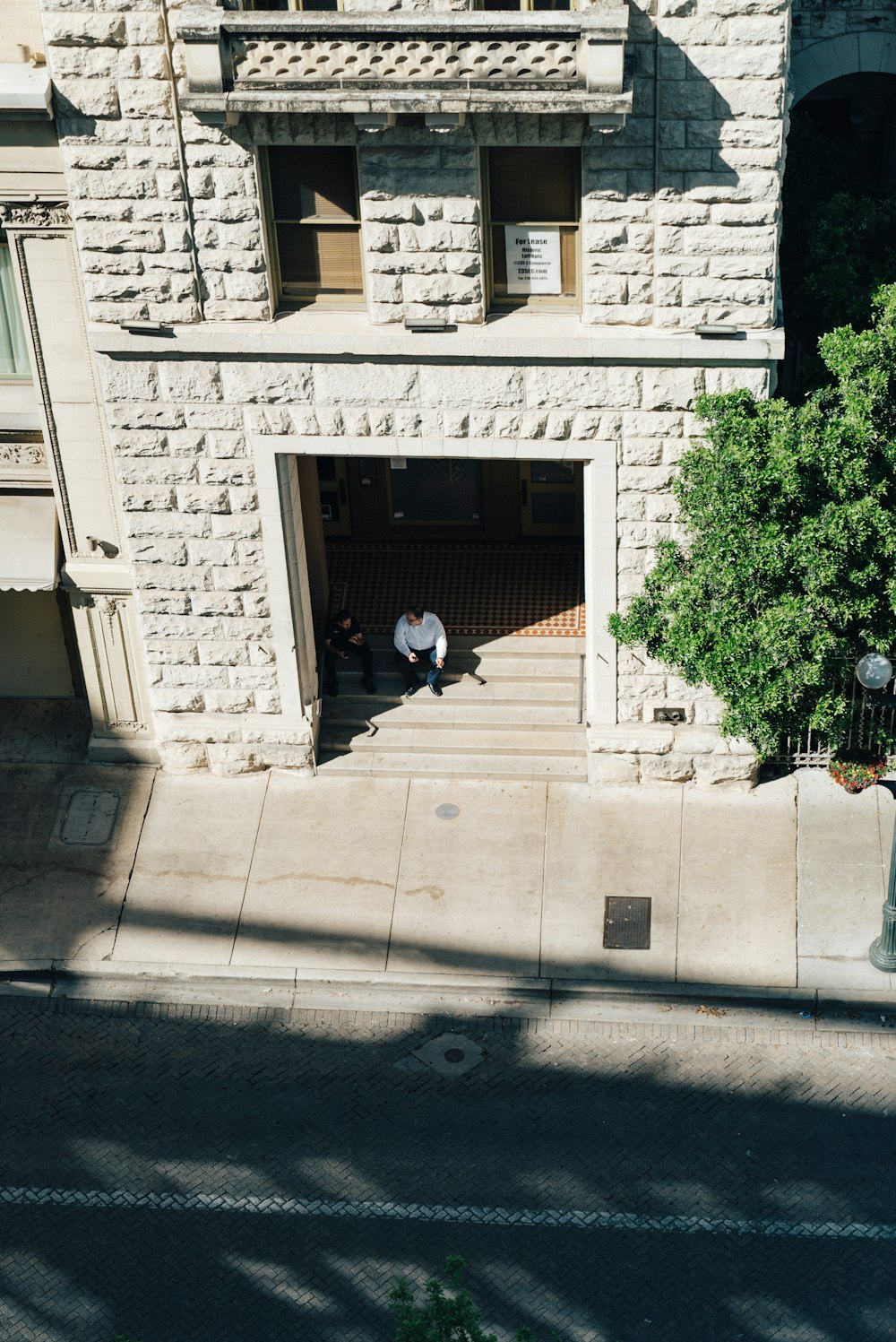 aerial photography of two persons sitting on a staircase of a building