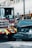 A fire truck and a black Nissan vehicle are involved in a collision at an urban intersection. The front of the car is severely damaged and white powder is visible on the ground, possibly from a fire extinguisher. The surroundings include city buildings and traffic lights.