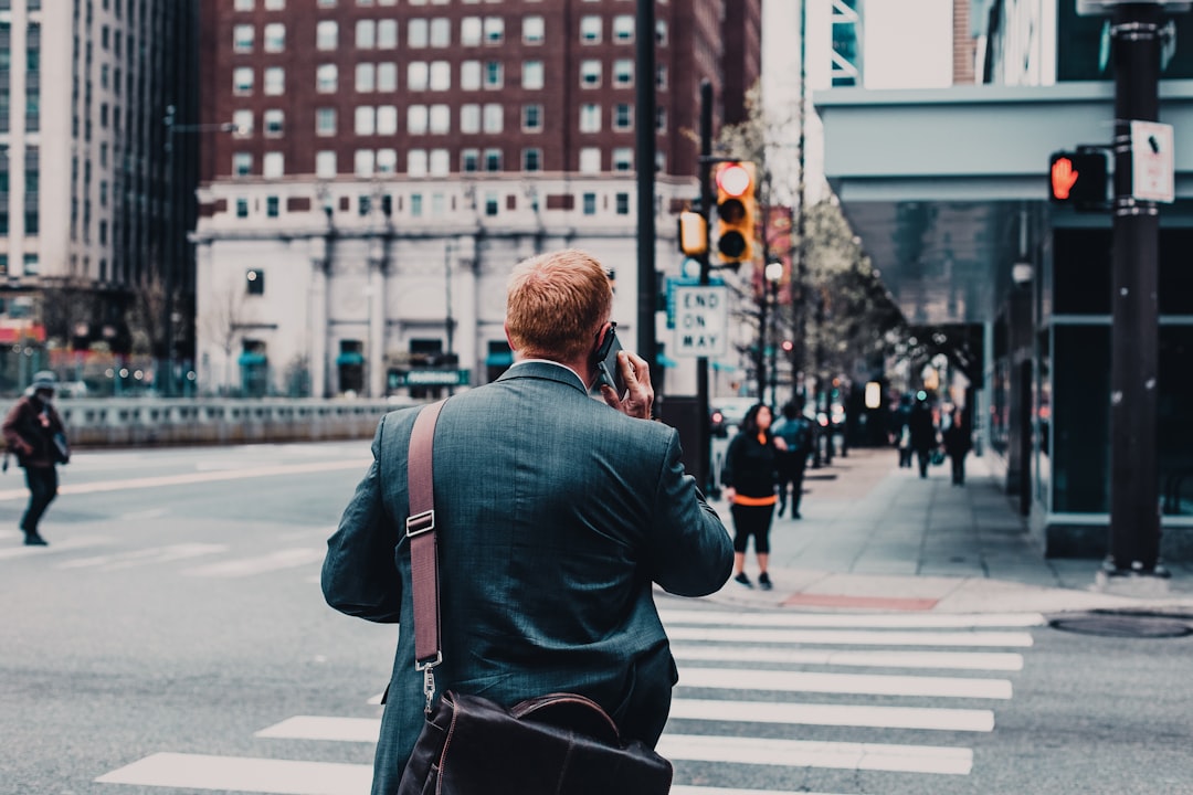 man talking on phone while crossing street