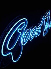 Blue neon lights spell out the word 'Good' against a dark background, with a sleek and modern design.