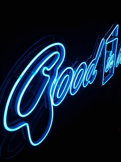 Blue neon lights spell out the word 'Good' against a dark background, with a sleek and modern design.