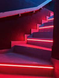 A futuristic digital staircase glowing in pink and orange neon lights.