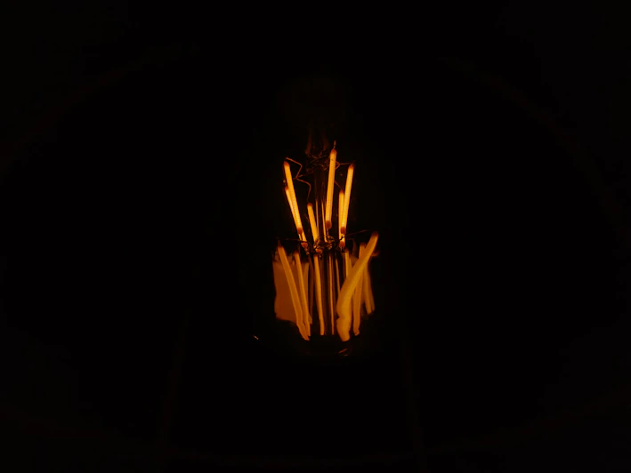 Close-up image of a vibrant, rusty orange filament spool glowing against a dark industrial background.