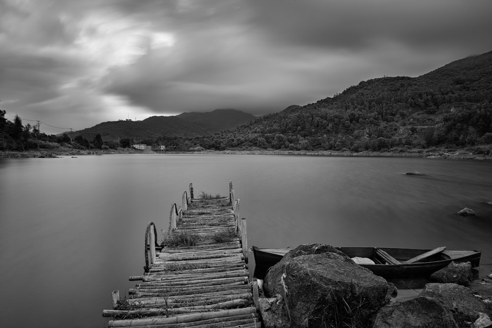 grayscale photo of dock and lake