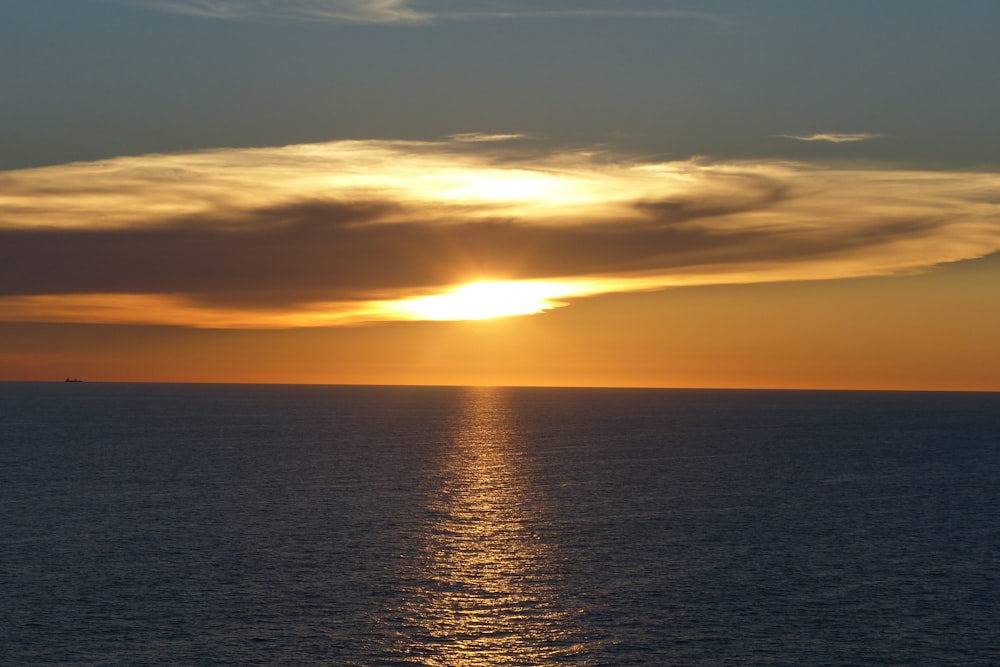 view of calm ocean and sun setting on horizon