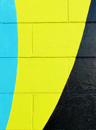 A vibrant mural in progress with an artist painting bold colors on a large wall.