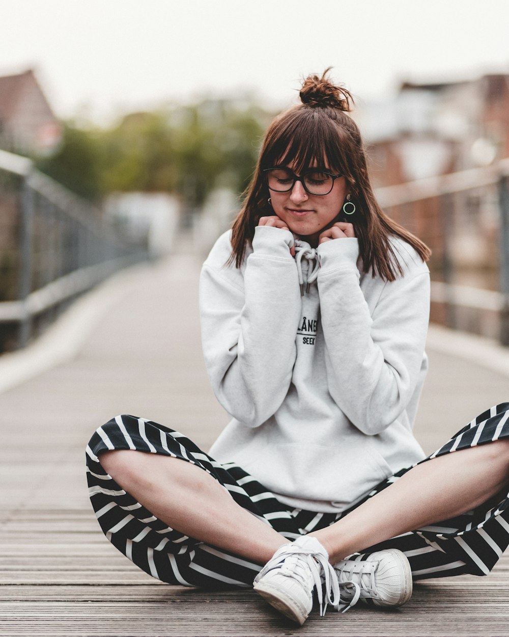 woman sitting on wooden pathway and touching her jacket