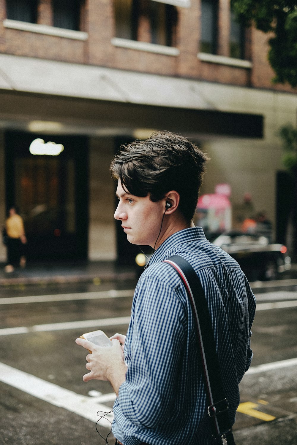 man standing while using earbuds and phone