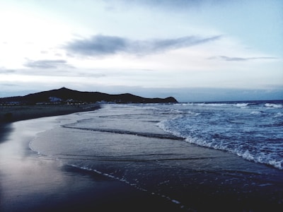 A peaceful beach scene with sun loungers and gentle waves at dawn.