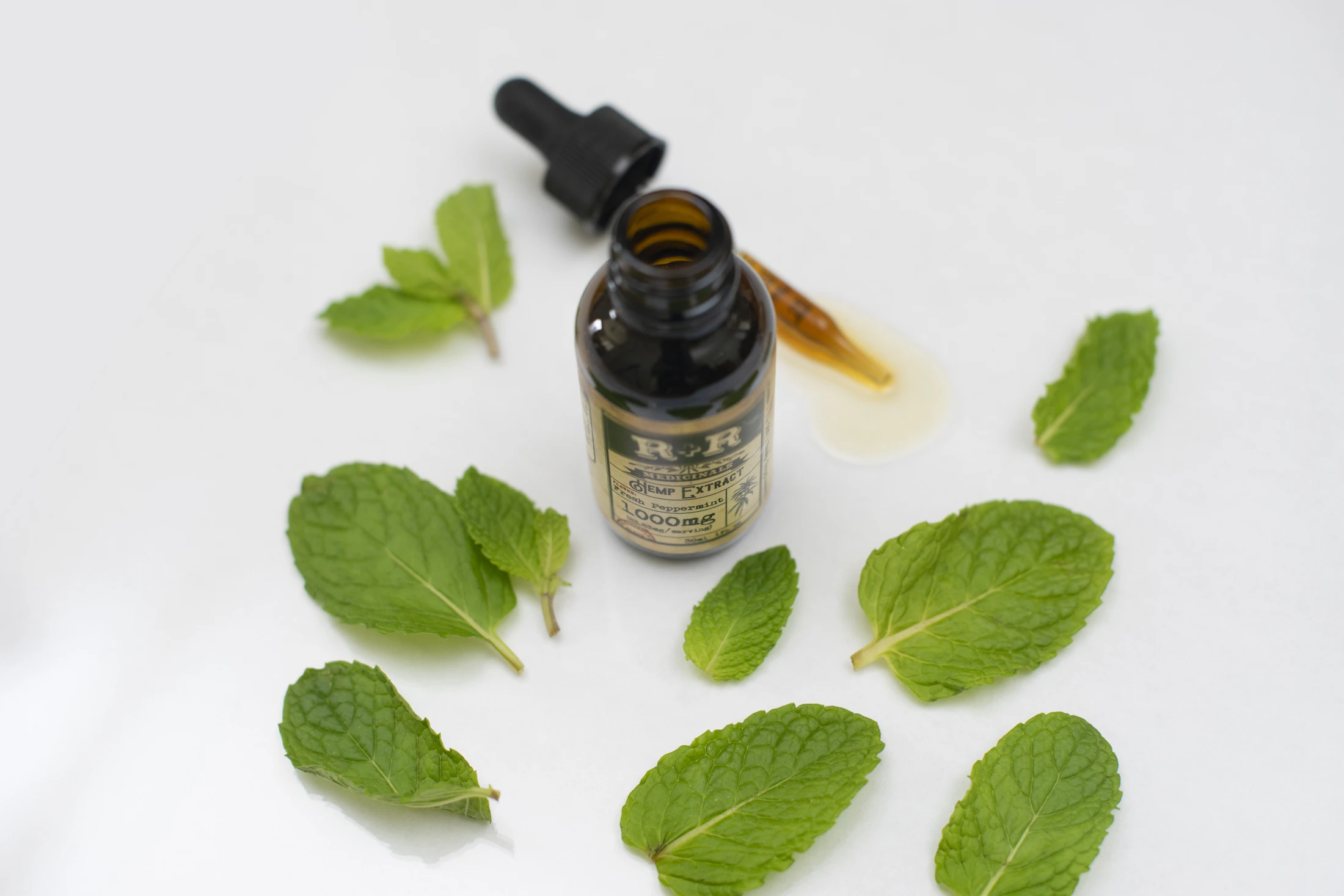 Essential-oil bottle surrounded by fresh green peppermint leaves