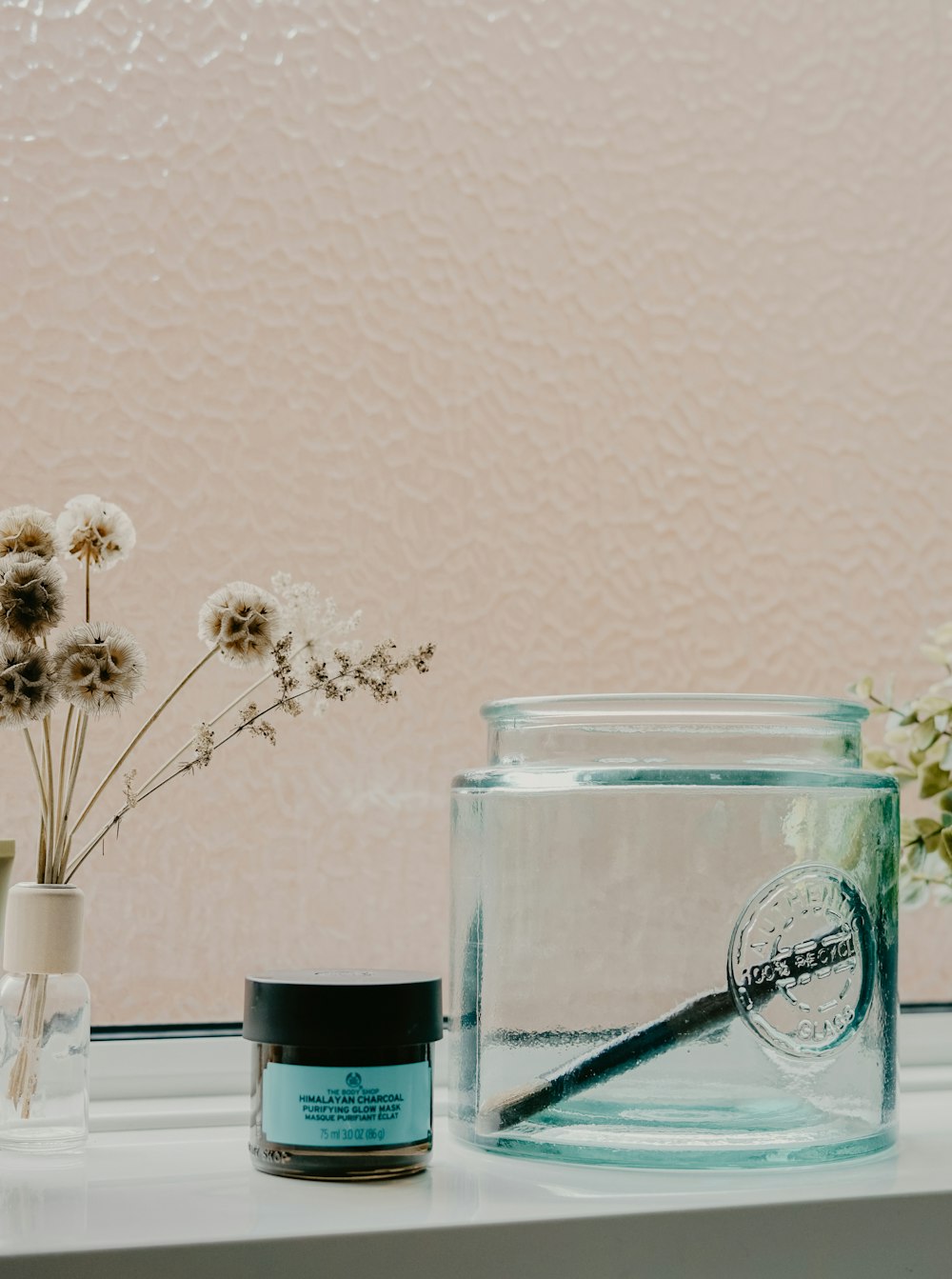 white and black labeled jar beside glass container