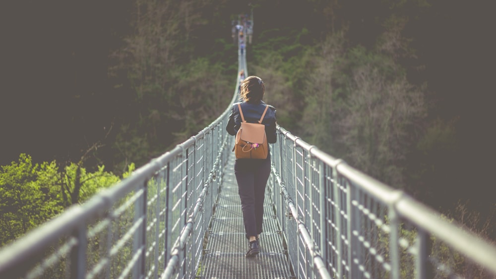 girl walking in gray bridge during daytime