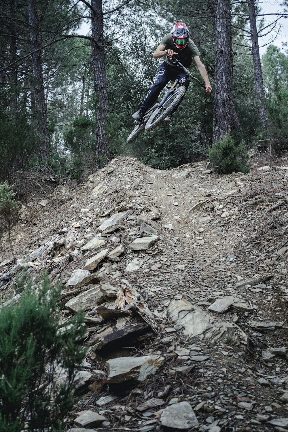 man riding mountain bike ramping on forest