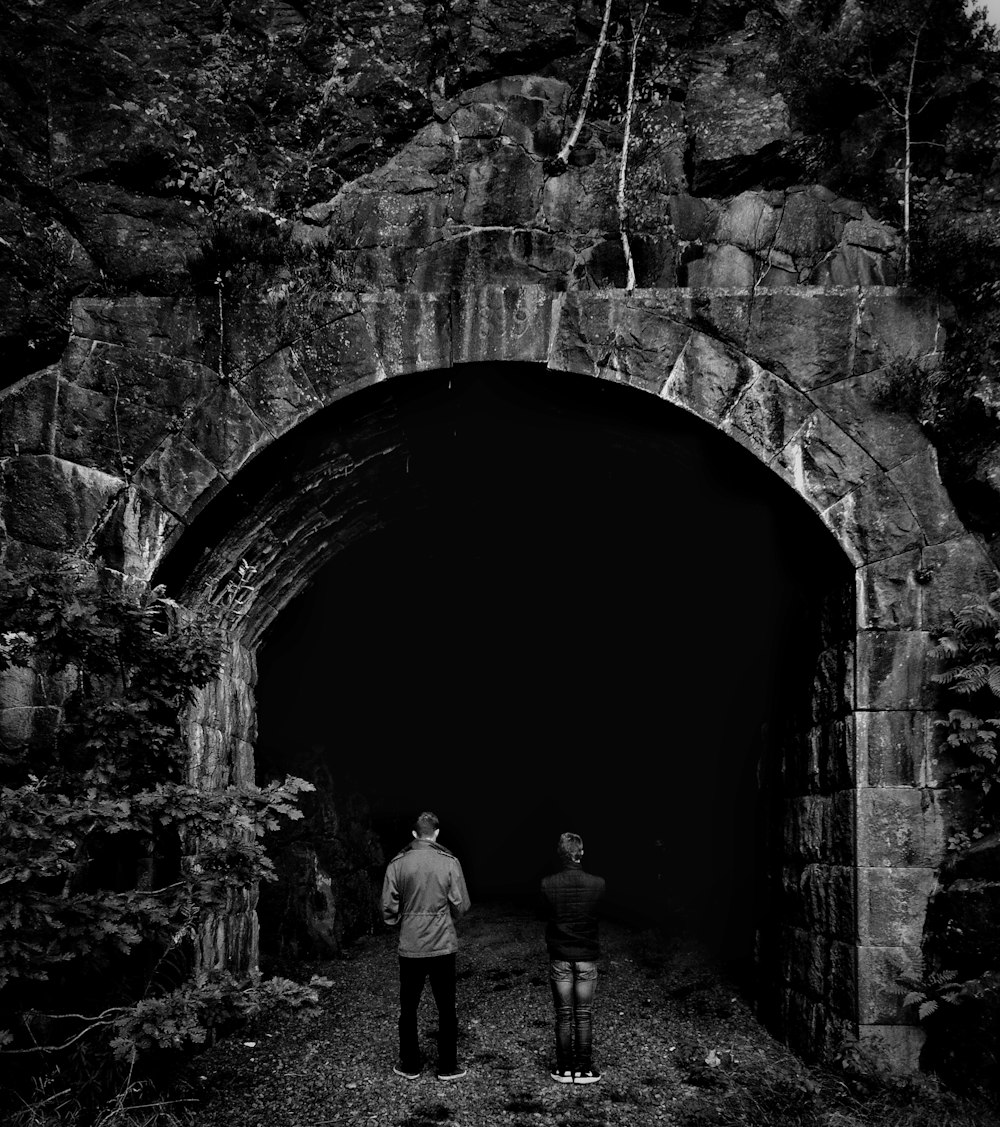 grayscale photo of two person facing tunnel