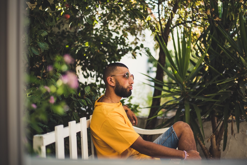 man sitting on bench near plants during daytime