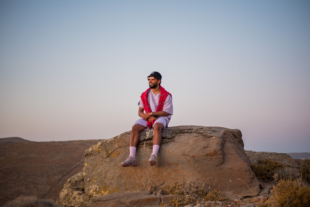 man sitting on brown rock