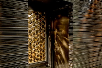 Geometric, metallic, textured wall design with a reflective surface creating a pattern of hexagonal shapes.
