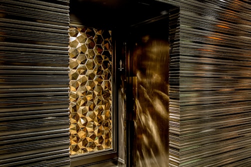 Geometric, metallic, textured wall design with a reflective surface creating a pattern of hexagonal shapes.