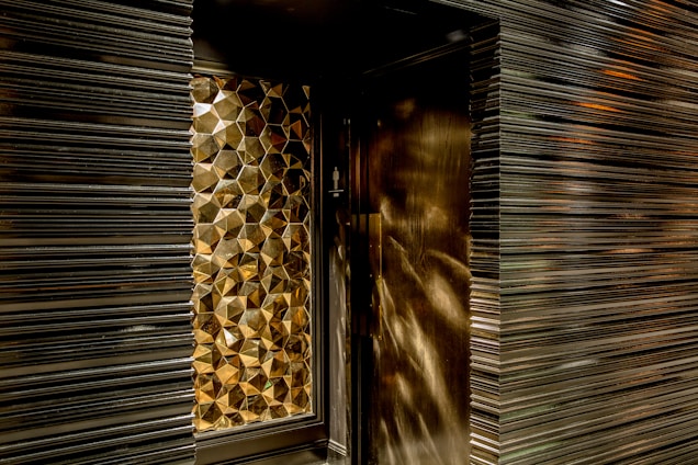 Geometric, metallic, textured wall design with a reflective surface creating a pattern of hexagonal shapes.