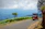 A couple enjoying a lush green landscape with a tuk tuk parked nearby under clear blue skies.