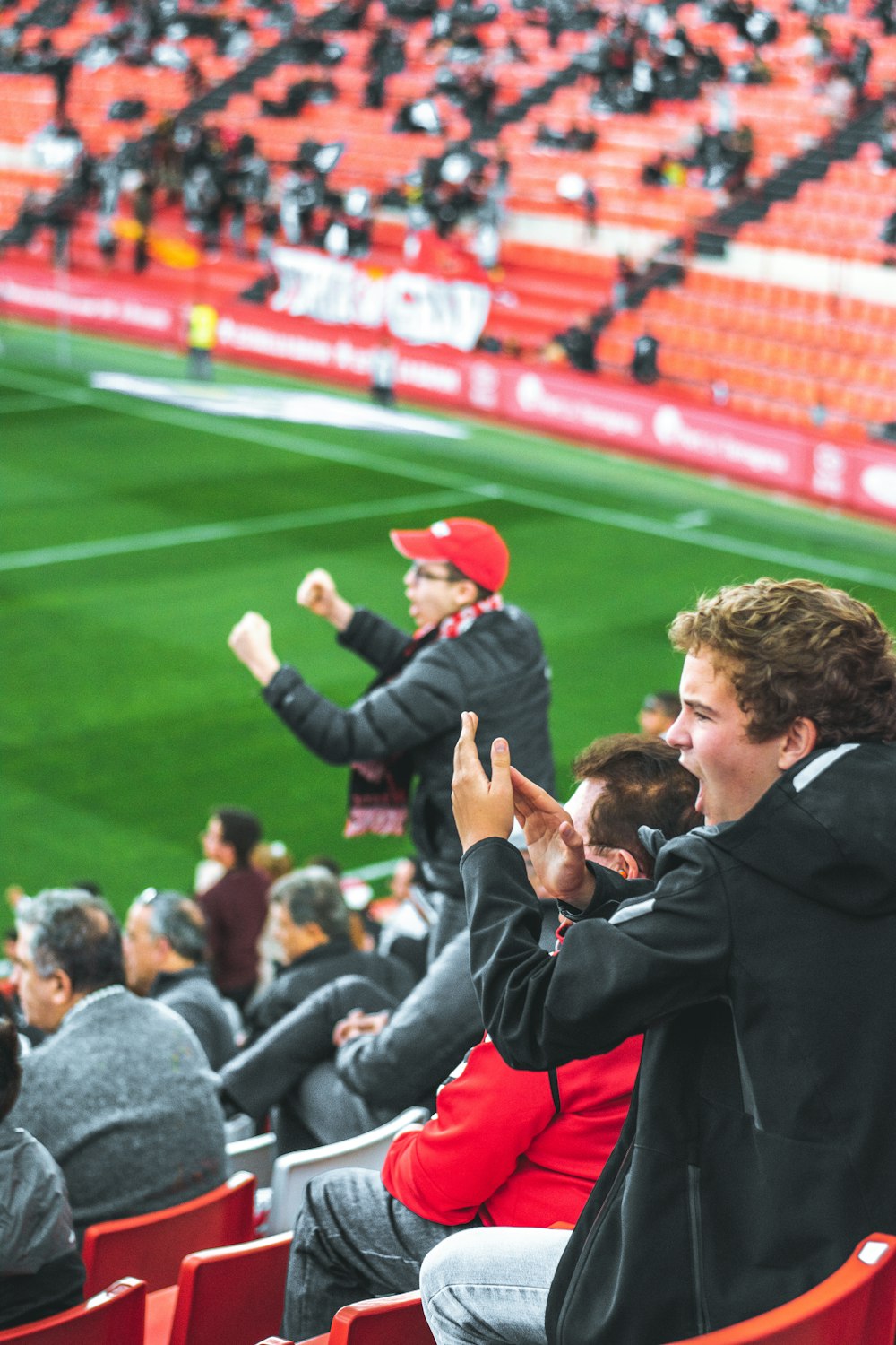 men at bleachers cheering on players on a sports field